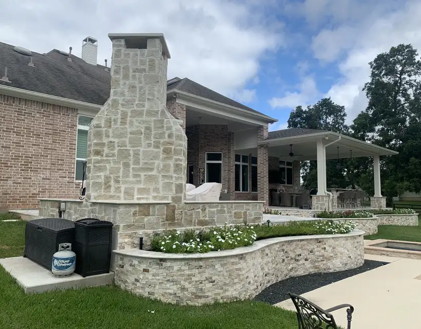 Stacked stone outdoor fireplace and curved stone planter wall at the Adamson backyard patio