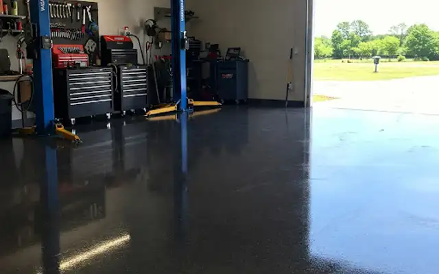 Glossy dark coated garage floor with car lifts and rolling tool chests