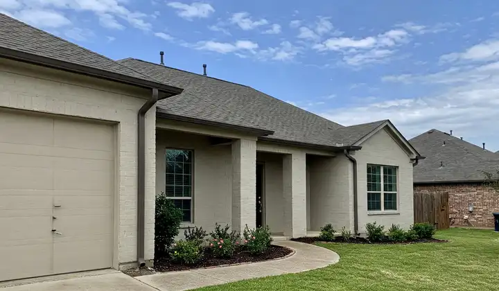 Painted brick home with gutters, downspouts and freshly mulched foundation shrub beds