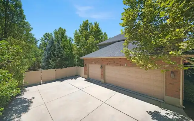 Large concrete driveway pad in front of a three-car garage surrounded by trees