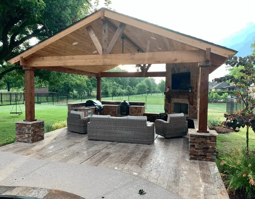 Cedar gable pavilion with stone column bases, outdoor fireplace and stamped concrete floor at the Guillot residence