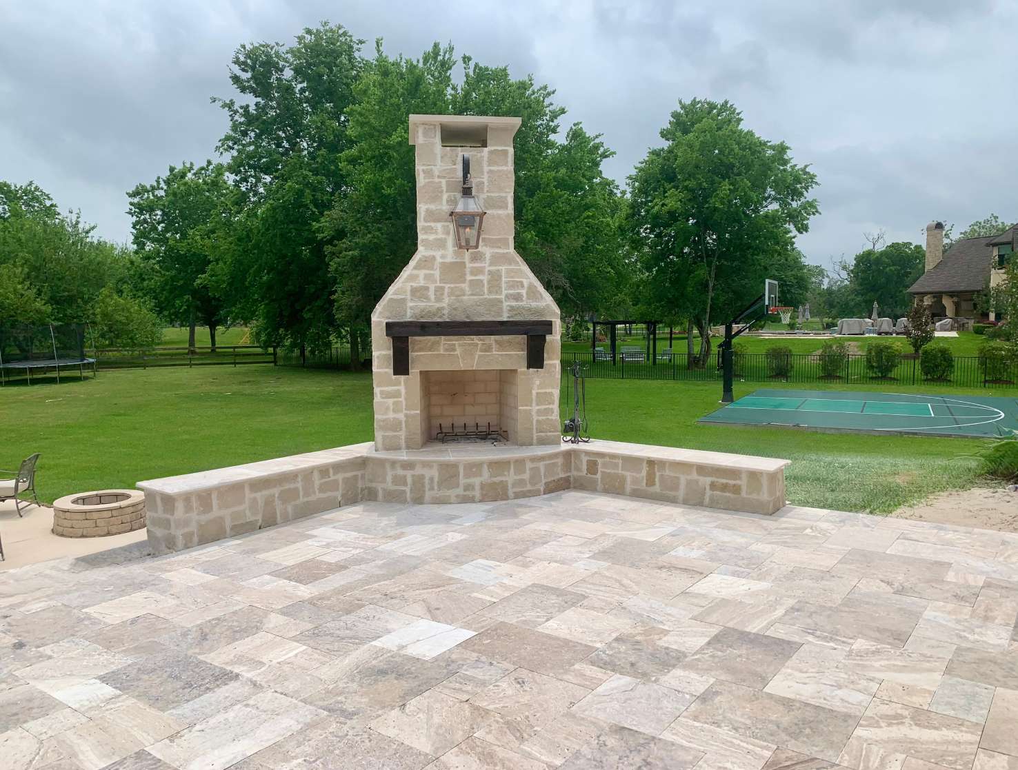 Limestone outdoor fireplace with seat walls on a travertine patio