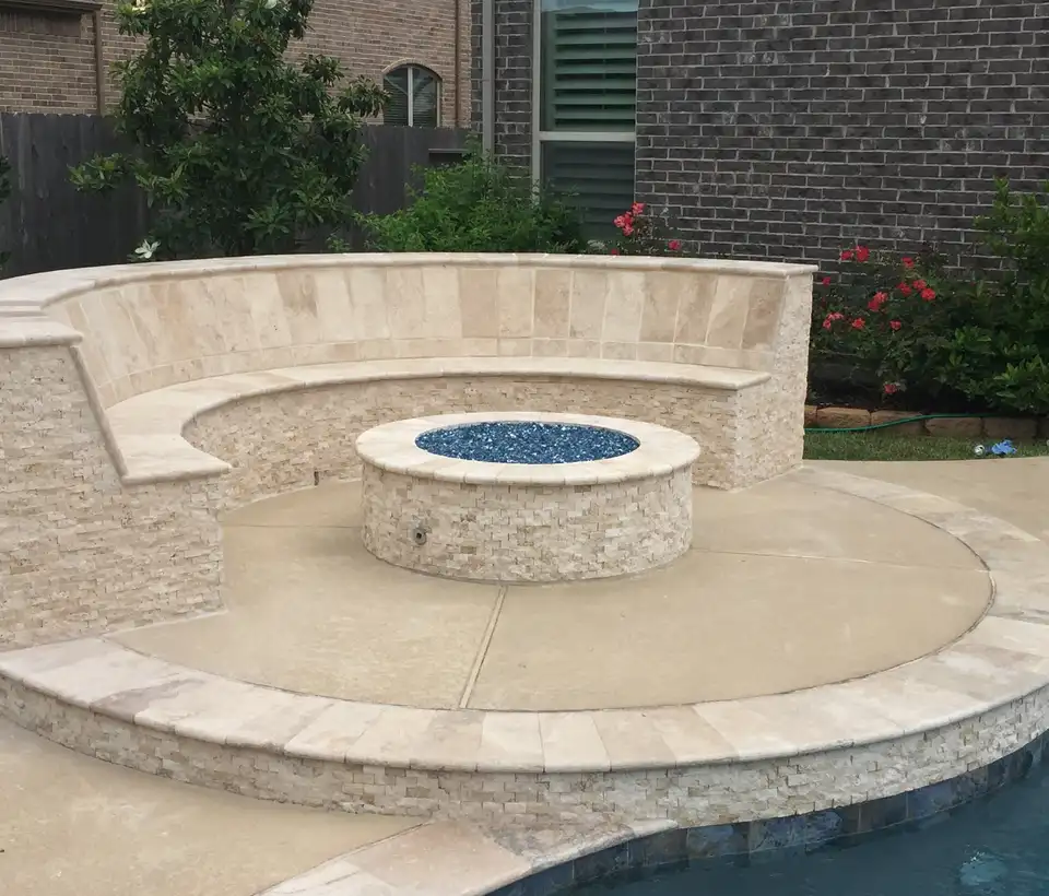 Stacked stone fire pit with blue fire glass and curved seat wall beside a Houston pool