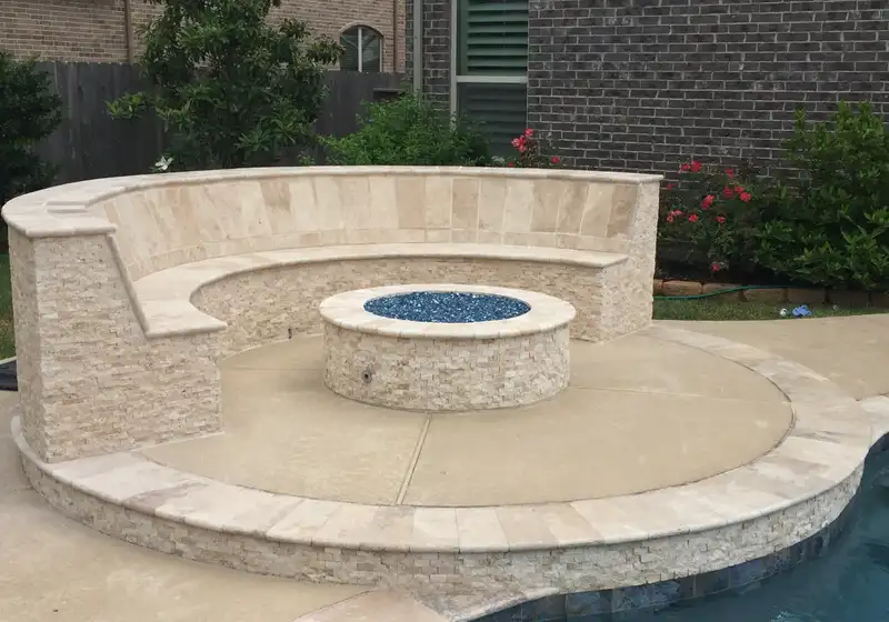 Stacked stone fire pit with blue fire glass and curved seat wall beside a Houston pool