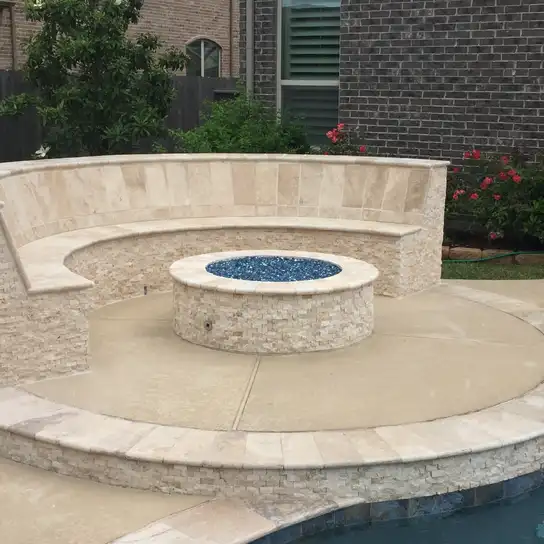 Stacked stone fire pit with blue fire glass and curved seat wall beside a Houston pool