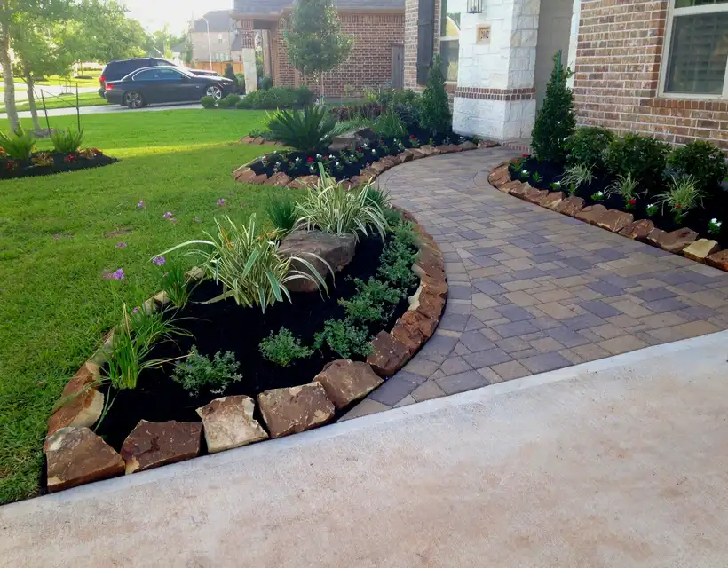 Curved paver walkway with boulder-edged planting beds at a Houston home entry