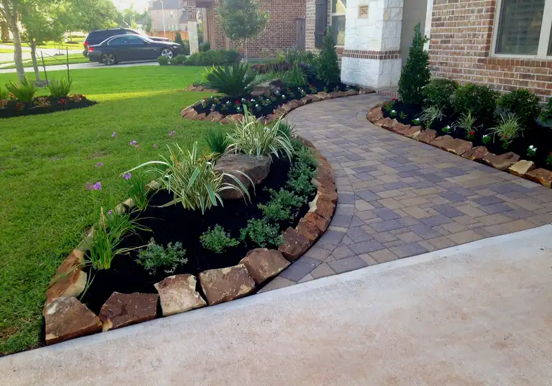 Curved paver walkway with boulder-edged planting beds at a Houston home entry
