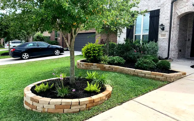 Stacked stone tree ring and raised planting bed border in a Houston front yard