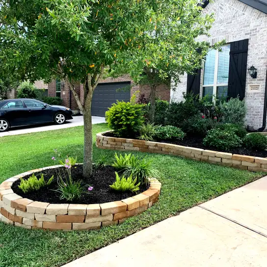 Stacked stone tree ring and raised planting bed border in a Houston front yard