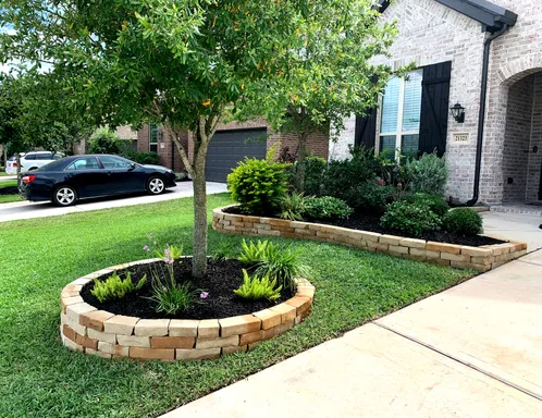 Stacked stone tree ring and raised planting bed border in a Houston front yard