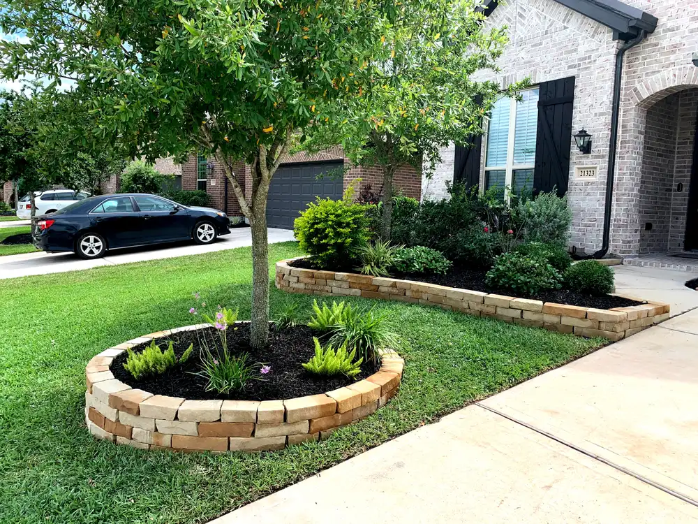 Stacked stone tree ring and raised planting bed border in a Houston front yard landscape