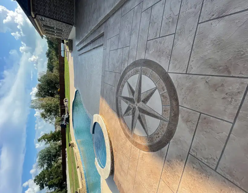 Stamped concrete pool deck with a compass rose medallion beside a Houston pool and spa