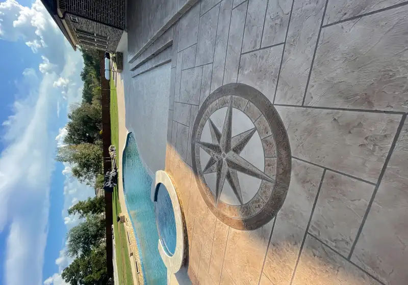 Stamped concrete pool deck with a compass rose medallion beside a Houston pool and spa