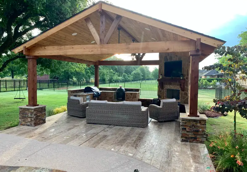 Cedar gable pavilion with stone fireplace, TV and wicker seating in a Houston backyard