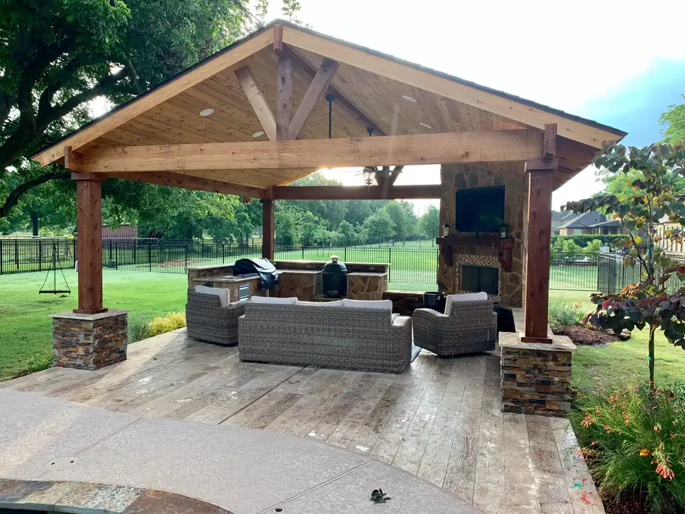 Cedar gable pavilion with stone fireplace, TV and wicker seating in a Houston backyard