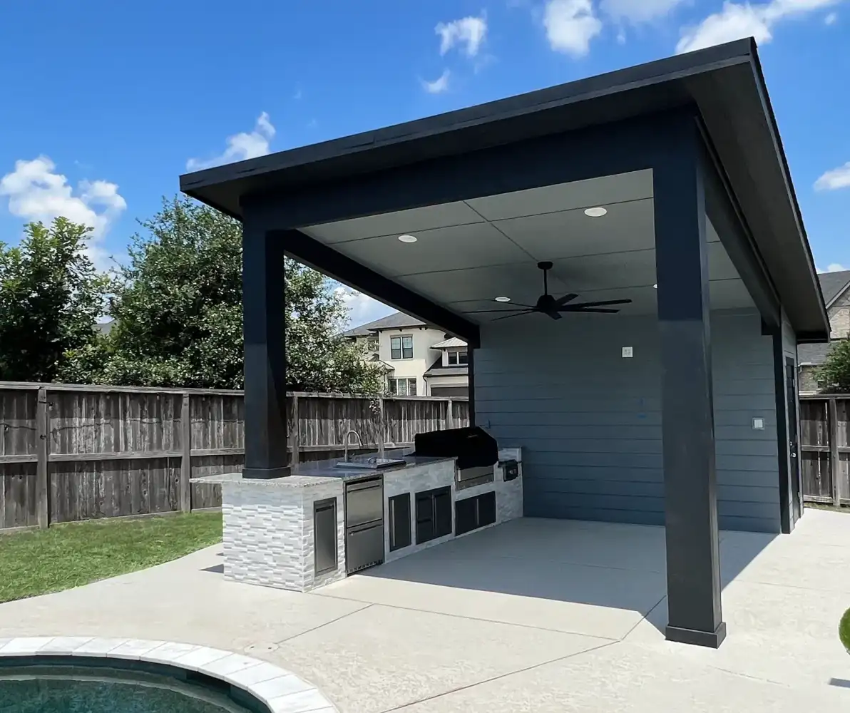 Modern dark pavilion with outdoor kitchen beside a Houston backyard pool and artificial turf