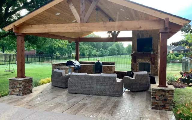 Cedar gazebo with a stacked stone fireplace, wall-mounted TV and wicker sofa set