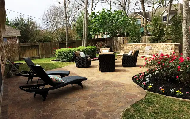 Stamped flagstone patio with lounge chairs, a stone seat wall and rose beds