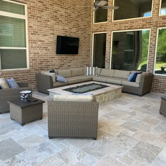 Travertine paver covered patio with stone fire table and wicker sectional seating