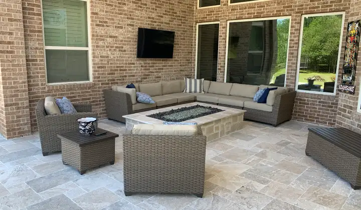 Travertine paver covered patio with stone fire table and wicker sectional seating