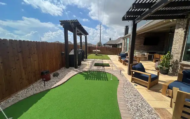 Two cedar pergolas, one attached and one freestanding, beside a backyard putting green