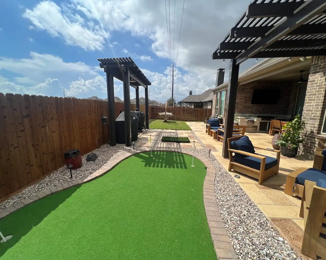 Backyard synthetic putting green with a paver border, pea gravel and cedar pergolas