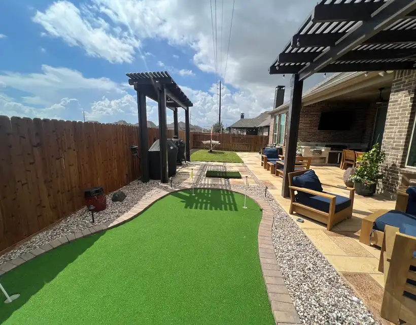 Cedar pergolas beside an artificial turf putting green and a paver patio