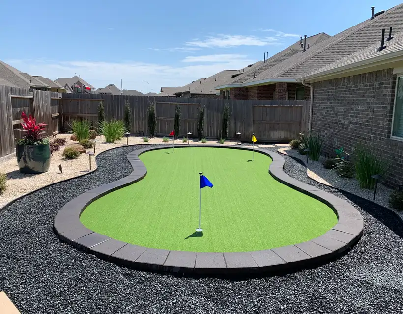 Kidney-shaped artificial putting green with flags, gray curb border and black river rock