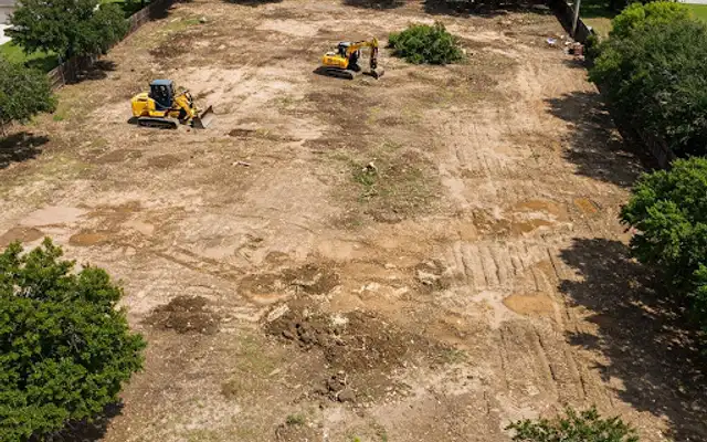 Aerial view of a cleared residential lot with a skid steer and mini excavator