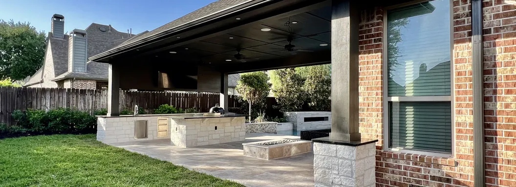 Patio cover with stone columns, outdoor kitchen and fire feature on a travertine patio