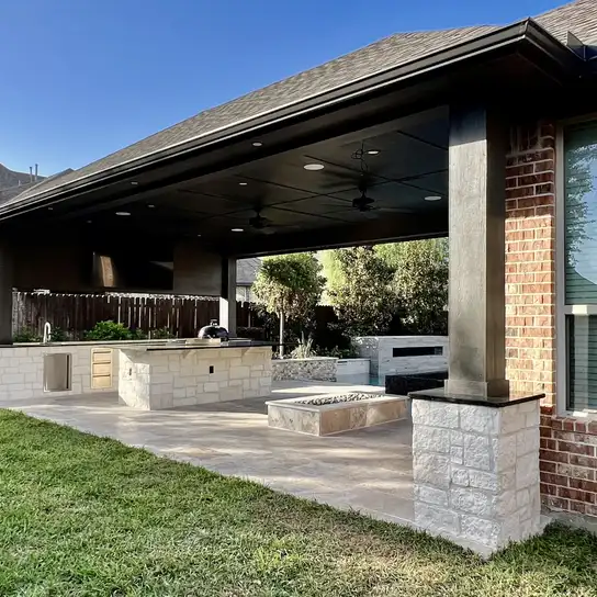 Patio cover with stone columns, outdoor kitchen and fire feature on a travertine patio