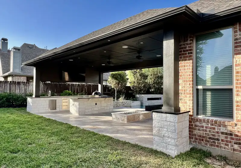 Patio cover with stone columns, outdoor kitchen and fire feature on a travertine patio