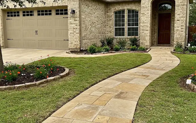 Flagstone walkway curving across a front lawn to a brick home entry