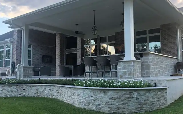 Large attached patio cover with bar seating above a curved stone planter wall