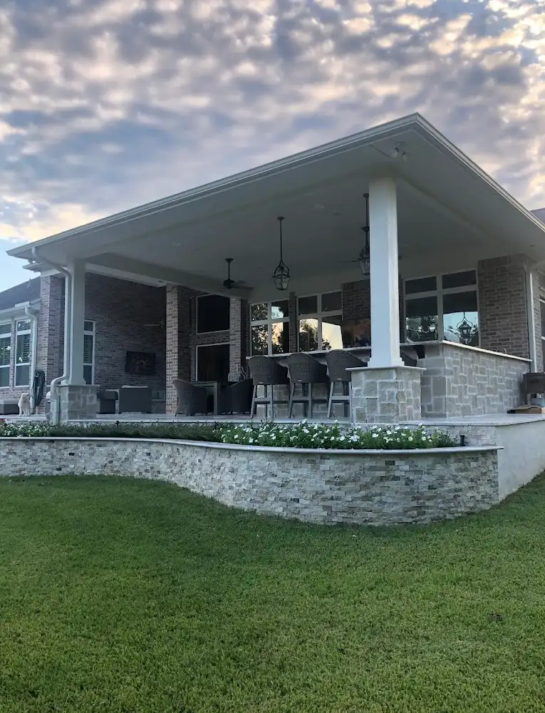Large covered patio with bar seating above a stacked stone planter wall at sunset