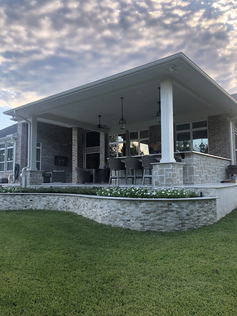 Large covered patio with bar seating above a stacked stone planter wall at sunset