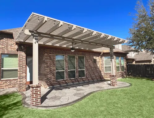 Painted pergola on brick columns over a stamped concrete patio with artificial turf