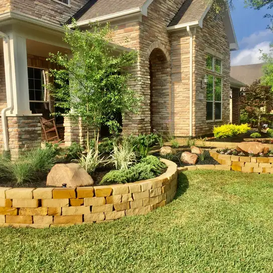 Stacked stone raised planting beds with boulders and ornamental grasses at a Houston home