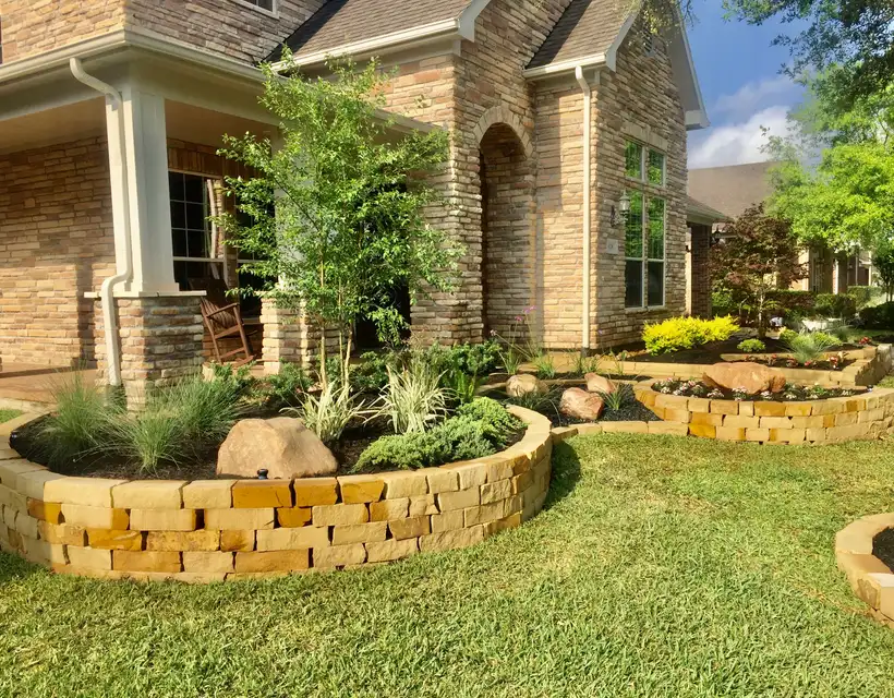 Front yard with raised stacked-stone planter beds, boulders and ornamental grasses