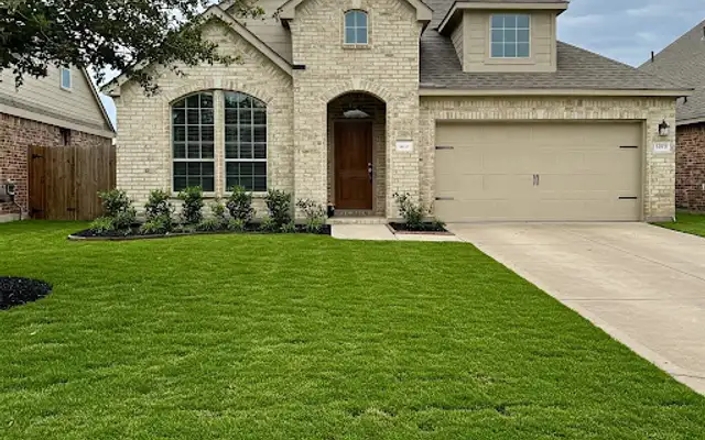 Lush, even front lawn after sod repair at a two-story brick house