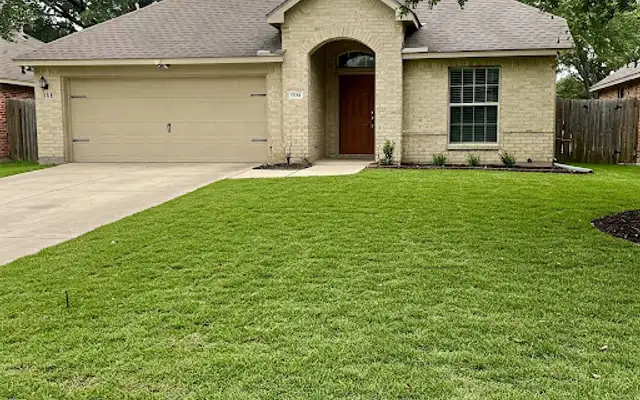 Healthy green front lawn in front of a brick and stone house