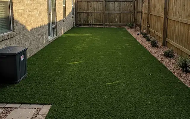 Narrow side yard covered in new artificial turf along a wood privacy fence