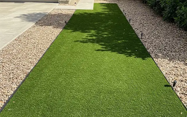 Strip of artificial turf between river rock beds leading to a home entry